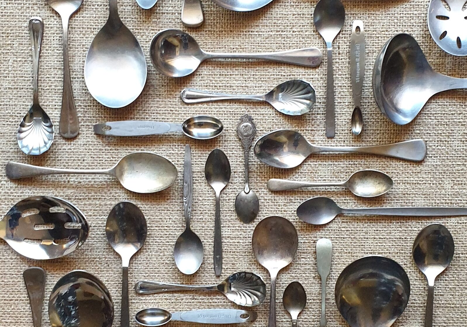 kitchen cutlery silverware spoon collection arranged neatly on table cloth full frame